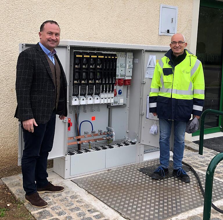 Grafenrheinfelds Bürgermeister Christian Keller (links) besichtigt mit Hartmut Schumm, Elektrofachkraft des Technischen Hilfswerks, den Einspeisepunkt für die externe Notstromversorgung in der Altmainsporthalle.