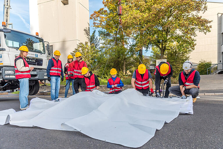 Sicherheit geht vor: Ausgestattet mit Warnwesten und Schutzhelmen haben die zehn Schülerinnen und Schüler ab 7 Uhr morgens das Gewebe aus dem Auto geholt, ausgerollt und dann so in Falten gelegt, dass die Vorhänge später so fallen wie geplant. Sicherheit geht vor: Ausgestattet mit Warnwesten und Schutzhelmen haben die zehn Schülerinnen und Schüler ab 7 Uhr morgens das Gewebe aus dem Auto geholt, ausgerollt und dann so in Falten gelegt, dass die Vorhänge später so fallen wie geplant.