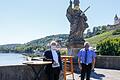 Achtsam sein: Die Brückenheiligen (hier der Heilige Kilian) auf der Alten Mainbrücke wurden mit einer Maske versehen. Auf ihr der Schriftzug 'Wir halten seit 295 Jahren Abstand!…' Am Fuße der Statue stehen Weihbischof Ulrich Boom (links) und Kommunalreferent Wolfgang Kleiner.
