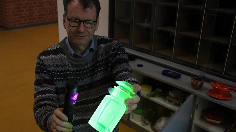 Radioaktivität sehen und hören: Martin Schwab bringt mit UV-Licht Uranglas zum Leuchten. Das Geschirr mit Uranglasur (rechts) lässt den Geigerzähler unaufhörlich rattern.