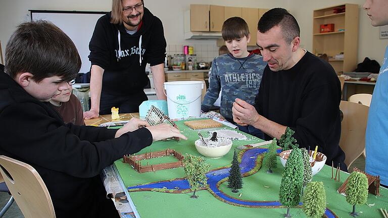 Karsten Müller (hinten links) und David Polotzek (rechts) arbeiten mit den Kindern an ihrem Steinzeitmodell, das im Rahmen des „talentCAMPus“-Ferienprogramms in Bad Königshofen entsteht. Karsten Müller (hinten links) und David Polotzek (rechts) arbeiten mit den Kindern an ihrem Steinzeitmodell, das im Rahmen des „talentCAMPus“-Ferienprogramms in Bad Königshofen entsteht.