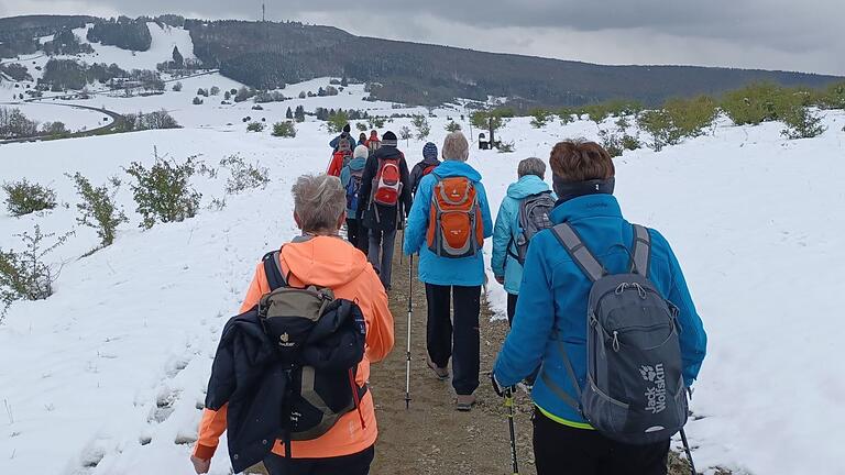 Wanderung auf den Kreuzberg mit schneebedeckten Hügeln im April.