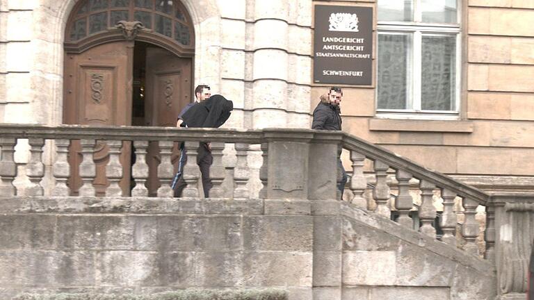 Hier wurde der Tatverdächtige - mit dem Mantel über dem Kopf - im März gerade von Polizisten  aus dem Landgericht Schweinfurt geführt, nachdem er dort eine Vorführung vor dem Haftrichter hatte. Foto: Sat1Bayern       -  Hier wurde der Tatverdächtige - mit dem Mantel über dem Kopf - im März gerade von Polizisten  aus dem Landgericht Schweinfurt geführt, nachdem er dort eine Vorführung vor dem Haftrichter hatte. Foto: Sat1Bayern