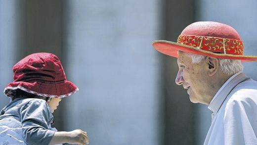 Gut behütet: Papst Benedikt XVI. trifft bei seiner wöchentlichen Audienz auf dem Petersplatz in Rom ein Kind.