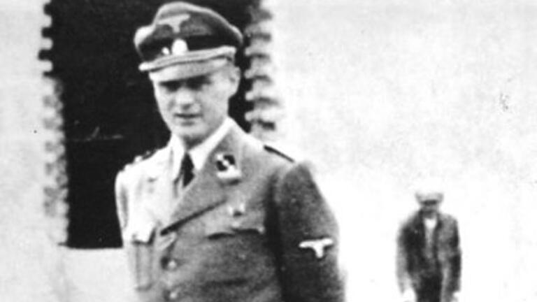KZ-Arzt Eduard Wirths in Auschwitz. Im Hintergrund bauen Zivilisten das Haus für die Familie.&nbsp;