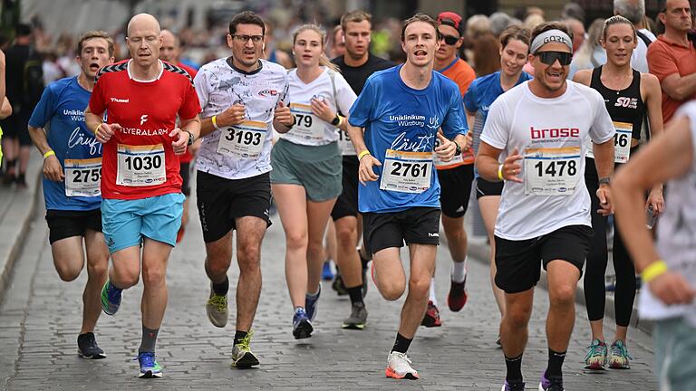 WUE2RUN - Firmenlauf       -  Zahlreiche Läuferinnen und Läufer überqueren am Donnerstag (29.06.23) im Rahmen des Firmenlaufs die Alte Mainbrücke in Würzburg.