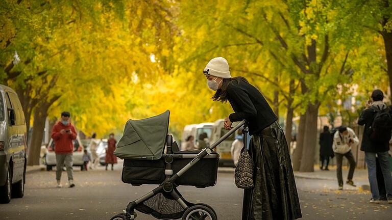 Frau mit Kinderwagen in Peking.jpeg       -  Frau mit Kinderwagen in Peking: Die Metropole wird von einer Krankheitswelle an Lungenentzündungen heimgesucht.