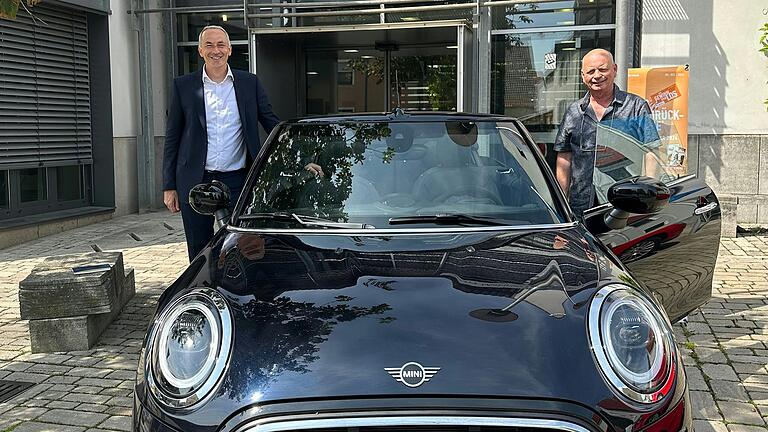 Privatkundenberater Dieter König VR-MainBank eG und Gerald Horling, der glückliche Gewinner mit seinem nagelneuen Mini Cooper Cabrio, vor der Geschäftsstelle in Bergtheim.