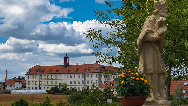 Blick auf das Kloster Heidenfeld mit dem Brückenheiligen Johannes Nepomuk im Vordergrund.