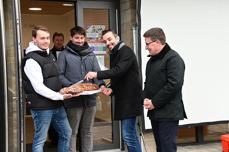 Bürgermeister Johannes Leibold zerschneidet den süßen Schlüssel, den es zur Übergabe von Architekt Albert Kastner geschenkt gab und der in der örtlichen Bäckerei Dittmann gebacken wurde. Ebenfalls bei der Einweihung war Landrat Christoph Schauder (rechts).