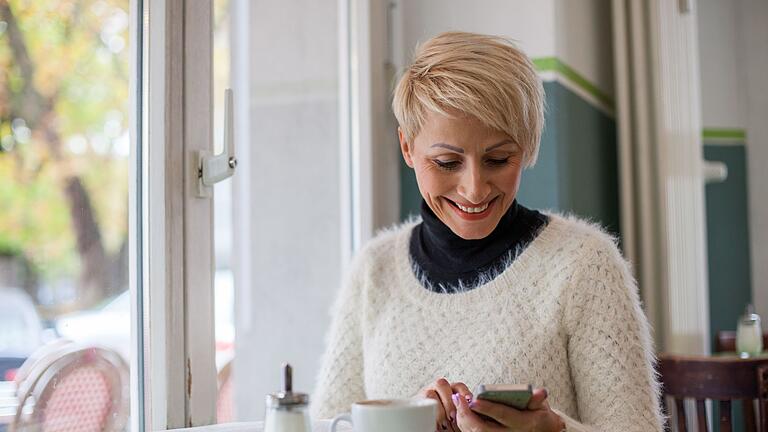 Frau schaut auf ein Smartphone       -  Für ein starkes soziales Netzwerk: Für Menschen ab 50 Jahren kann das Internet die psychische Gesundheit verbessern und die Zufriedenheit steigern.