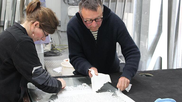 Filigrane Arbeit: Glasmeisterin Annika Esser und Stadtheimatpfleger Dr. Harald Knobling ziehen die Schutzfolie nach der Sandstrahlung mühsam von der Scheibe ab.