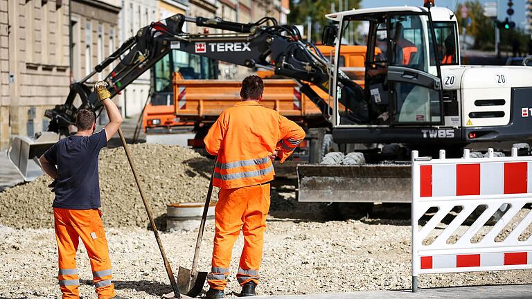 Zwei Bauarbeiter beim Verteilen von Kies an einer Baustelle. Anlieger mussten für den Straßenausbau in der Vergangenheit kräftig mitbezahlen.