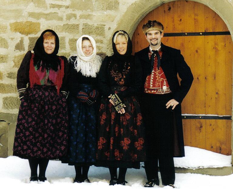 Ein Winterbild aus dem Jahr 2001: Drei Frauen in Festtracht mit der Winter-Hinterbind-Hulla. Männertracht mit langer Hose und Pelzkappla.