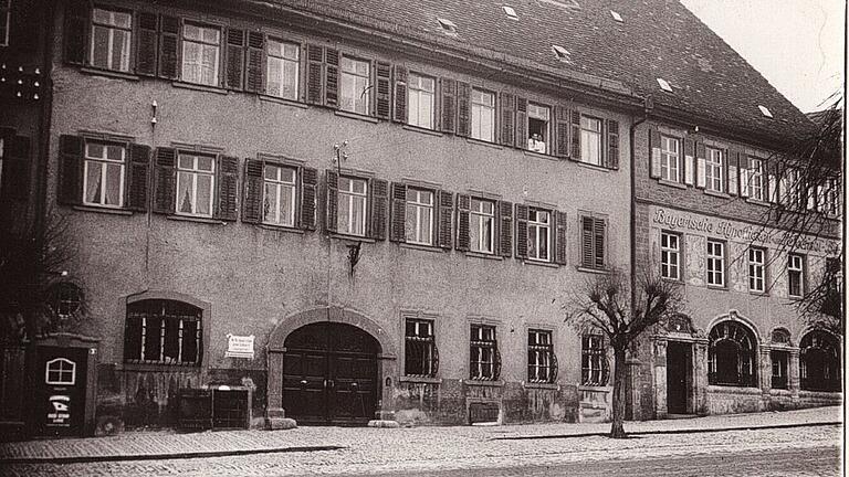 Die Hypotheken- und Wechselbank mit ihrem Nebengebäude um das Jahr 1930: Der jüdische Zahnarzt Dr. Hermann Schur schaut mit einer Helferin zum Fenster raus. Im Zweiten Weltkrieg wurde das Areal zum Kriegsgefangenenlager.