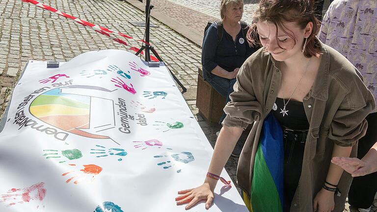 Bei der Mitmachaktion konnten Personen durch ihren bunten Handabdruck auf dem Plakat der Gruppe ihr Engagement zur Stärkung der Demokratie bekunden.