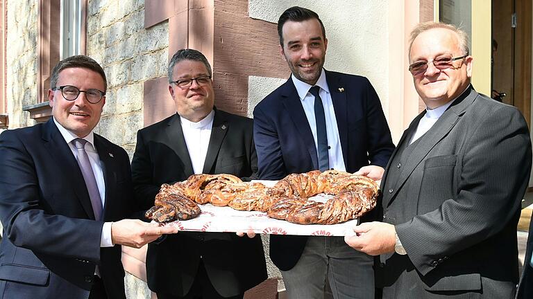 Mit einem symbolischen Schlüssel als Nusszopf wurde die Wiedereröffnung des ehemaligen Rathauses in Gerchsheim gefeiert. Auf dem Bild von links nach rechts: Landrat Christoph Schauder, Generalvikar Christoph Neubrand, Bürgermeister Johannes Leibold und Pfarrer Dr. Damian Samulski.