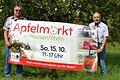 Bürgermeister Friedolin Link (links) und Adam Zentgraf vom Arbeitskreis Streuobst der Gemeinde Hausen präsentieren im Streuobstlehrpfad das diesjährige Werbebanner für den Apfelmarkt am 15. Oktober.