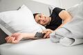 Mann liegt lächelnd morgens im Bett       -  Guten Morgen! Es gibt Tricks, mit denen sich die Zeitumstellung besser wegstecken lässt.