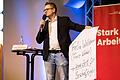 Moderator Viktor Grauberger mit einem Plakat über Direktkandidat Felix Wallström, der die Veranstaltung kurzfristig abgesagt hatte.