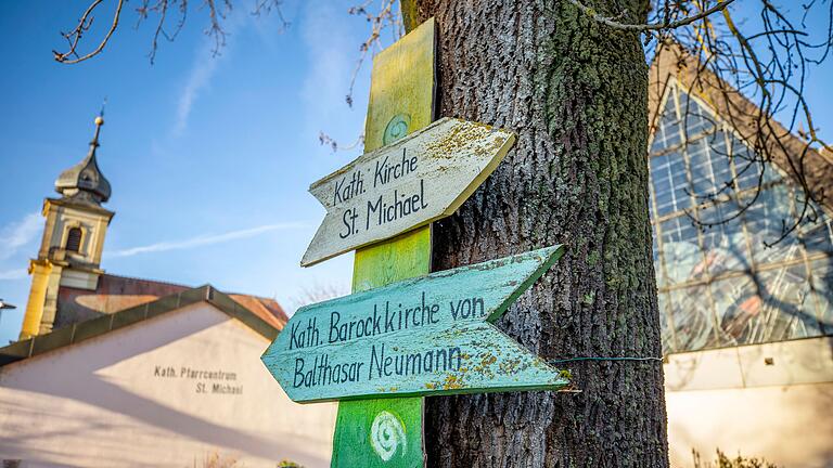 Wegweiser in Euerbach vor der alten Barockkirche (links) und der neuen Kirche (rechts). Die Gemeinde im Landkreis Schweinfurt muss sich entscheiden, welche der beiden die Hauptkirche sein soll.&nbsp;