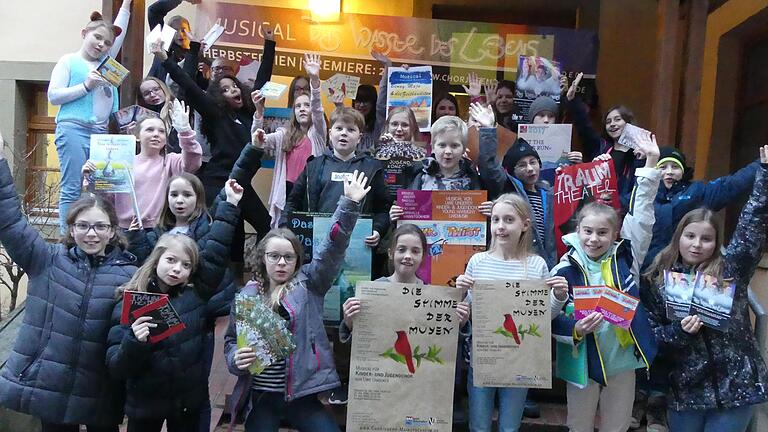 Fröhliche junge Sänger: Die mittlere Gruppe (Kinderchor Young Harmony) vor dem Johann-Heinrich-Zang-Haus in Mainstockheim. In den Händen halten die Kinder Plakate, Flyer, CDs, Programmhefte vergangener Konzertauftritte, Projekte und Musicals.