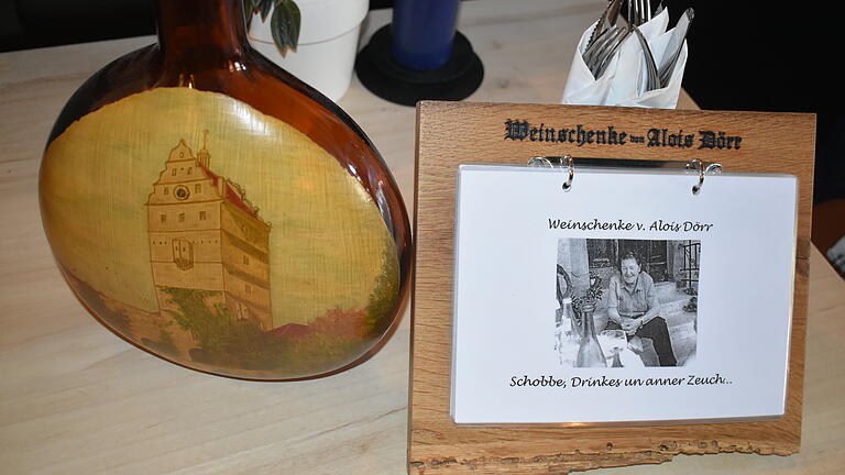 Ganz viel Tradition: Ein alter Bocksbeutel mit dem Bad Neustädter Hohntor und die Weinkarte aus dem alten Eichenholz.