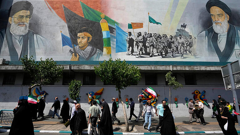 Nahostkonflikt - Iran.jpeg       -  Iranische Gläubige gehen an einem Wandgemälde vorbei, das den verstorbenen Revolutionsgründer Ayatollah Khomeini zeigt. Wie weit kann der Konflikt im Nahen Osten eskalieren?