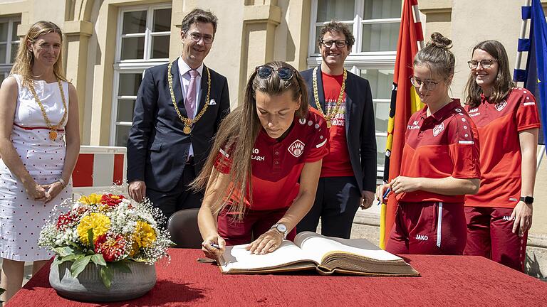 Wie das Männerteam durfte sich auch die Frauenmannschaft des FC Würzburger Kickers (vorne Medina Desic) nach dem Aufstieg in die Zweite Bundesliga am 6. Juli ins Goldene Buch der Stadt Würzburg eintragen. Im Hintergrund (von links) Sportbürgermeisterin Judith Jörg, Oberbürgermeister Christian Schuchardt und Klimabürgermeister Martin Heilig und zwei Spielerinnen. Wie das Männerteam durfte sich auch die Frauenmannschaft des FC Würzburger Kickers (vorne Medina Desic) nach dem Aufstieg in die Zweite Bundesliga am 6. Juli ins Goldene Buch der Stadt Würzburg eintragen. Im Hintergrund (von links) Sportbürgermeisterin Judith Jörg, Oberbürgermeister Christian Schuchardt und Klimabürgermeister Martin Heilig und zwei Spielerinnen.