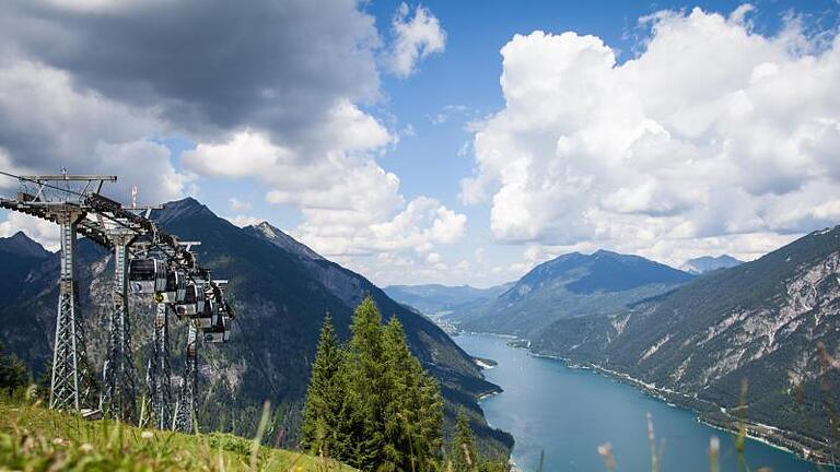 Zumindest die Kulisse ist perfekt: Wer das Surfen am Achensee lernt, hat ein grandioses Bergpanorama um sich. Foto: Tourismusverband Achensee/dpa-tmn       -  Pertisau liegt am südwestlichen Ufers des größten Sees in Tirol: dem Achensee. Im Sommer können sich Urlauber sich hier am Strandbad eine Auszeit gönnen.