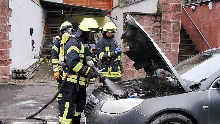 Opel brennt in der Bad Kissinger Schönbornstraße       -  Die Feuerwehr Garitz kühlt den gelöschten Motorraum des Opels mit einem kräftigen Wasserstrahl.