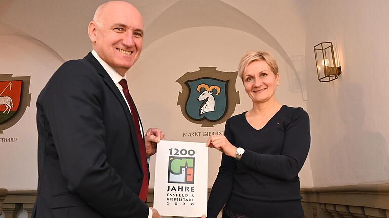 Organisations-Chefin Annette Barreca und Bürgermeister Helmut Krämer mit dem Logo, mit dem sich Giebelstadt im Jubiläumsjahr präsentiert.&nbsp;