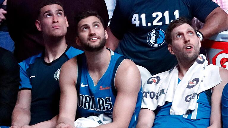 Dwight Powell, Maximilian Kleber und Dirk Nowitzki von den Dallas Mavericks verfolgen eine Ehrung per Video für Nowitzki nach dessen letztem Heimspiel.