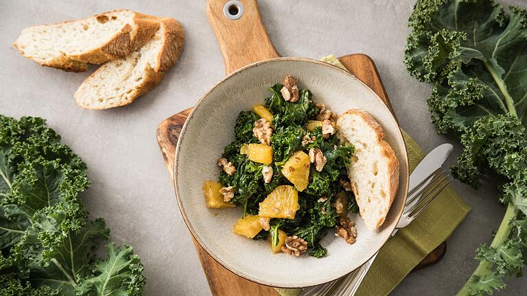 Grünkohlsalat mit Orangen und Walnüssen       -  Grünkohl schmeckt auch als Salat, zum Beispiel mit Nüssen und einem kräftig-würzigen Dressing.