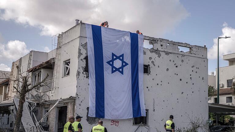 Nahostkonflikt - Kiriat Bialik       -  Eine riesige israelische Fahne hängt vom Dach eines beschädigten Gebäudes in Kiriat Bialik.