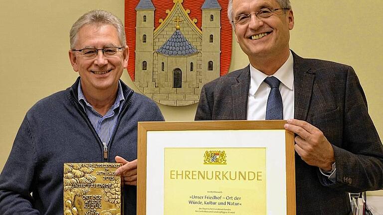 Stolz auf den schönsten Friedhof im Landkreis: Bürgermeister Eberhard Streit (rechts) und Helmut Dietz von der VG Mellrichstadt präsentieren die Urkunde und die Bronzeplakette, mit denen der Parkfriedhof in Mellrichstadt ausgezeichnet wurde. Stolz auf den schönsten Friedhof im Landkreis: Bürgermeister Eberhard Streit (rechts) und Helmut Dietz von der VG Mellrichstadt präsentieren die Urkunde und die Bronzeplakette, mit denen der Parkfriedhof in Mellrichstadt ausgezeichnet wurde.