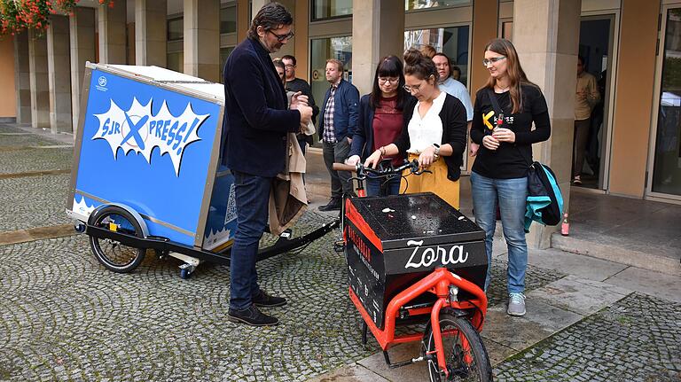 Rad und Hänger sind zusammen keine Leichtgewichte, ein Elektroantrieb hilft beim Strampeln. Stadtrat Ralf Hofmann und Interessierte begutachten den sjrXpress. Rad und Hänger sind zusammen keine Leichtgewichte, ein Elektroantrieb hilft beim Strampeln. Stadtrat Ralf Hofmann und Interessierte begutachten den sjrXpress.