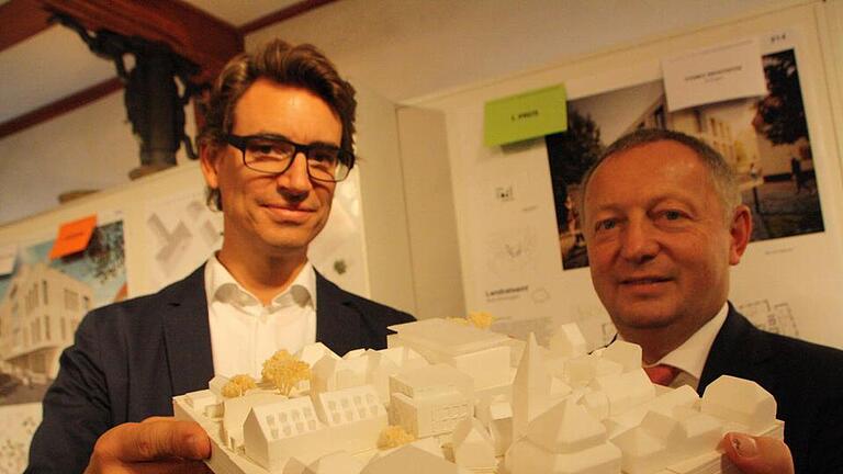 Architekt Thomas Steinle und Landrat Thomas Bold mit dem Modell des Erweiterungsbaus: Durch die zum Teil zwei- und zum Teil dreigeschossige Bauweise fügt sich das Gebäude (Bildmitte) gut in das Ensemble zwischen Rathaus (vorne), Jakobuskirche (rechts) und Landratsamt (dahinter) ein. Fotos: Ralf Ruppert       -  Architekt Thomas Steinle und Landrat Thomas Bold mit dem Modell des Erweiterungsbaus: Durch die zum Teil zwei- und zum Teil dreigeschossige Bauweise fügt sich das Gebäude (Bildmitte) gut in das Ensemble zwischen Rathaus (vorne), Jakobuskirche (rechts) und Landratsamt (dahinter) ein. Fotos: Ralf Ruppert