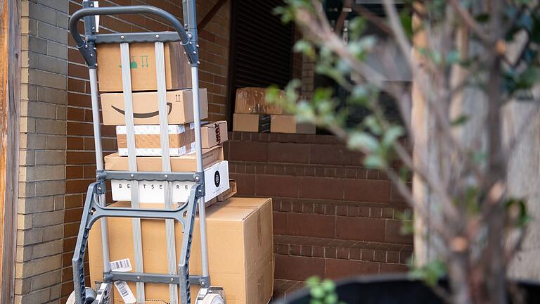 Paketmenge wächst wieder leicht       -  Pakete stehen auf einer Karre, während ein Paketzusteller Pakete ausliefert.