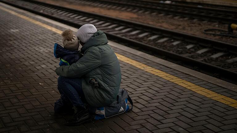 Eine Frau und ihr Kind schauen auf einen abfahrenden Zug, als sie am Bahnhof von Kiew in der Ukraine zu fliehen versuchen.