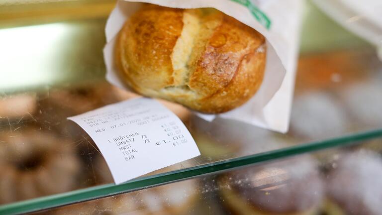 Ein Brötchen und der dazugehörige Kassenbon liegen auf der Theke einer Feinbäckerei.&nbsp;Wenige Tage nach Inkrafttreten der umstrittenen Kassenbonpflicht stößt die Regelung vor allem bei Bäckereien auf Kritik.&nbsp;