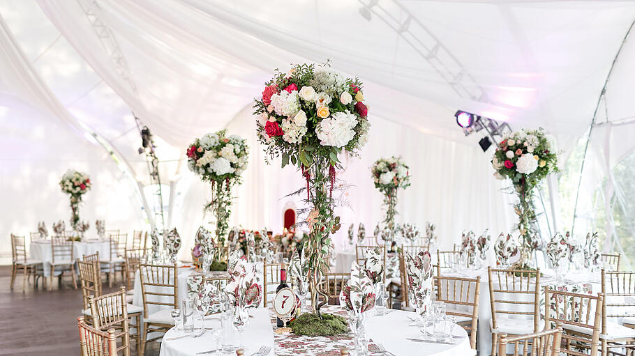 hochzeitszelt       -  Hochzeit im Strechzelt mit langen weißen Vorhängen an Zeltdecke und -wänden und traumhaften Blumengestecken als Tischdekoration.
