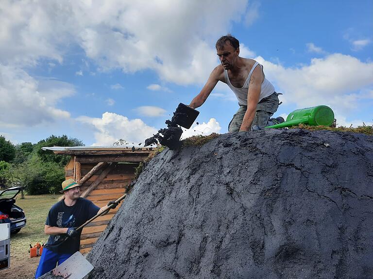 Wenn der Meiler fertig aufgebaut ist, dichten ihn die Helfer mit Sandboden ab. Wenn der Meiler fertig aufgebaut ist, dichten ihn die Helfer mit Sandboden ab.