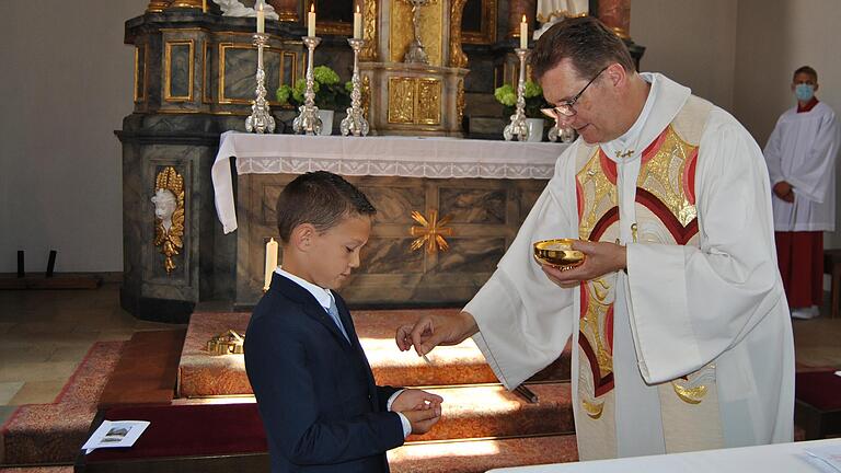 Der 'Weiße Sonntag' ist ein besonderer Ehrentag im Leben junger katholischer Mädchen und Jungen. Sie gehen zum ersten Mal zum Tisch des Herrn und empfangen, wie hier Luca von Pfarrer Andreas Krefft, die heilige Kommunion.&nbsp;