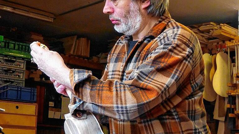 Gitarrenbauer Hermann Gräfe in seiner Werkstatt mit einer Cavaquinho.