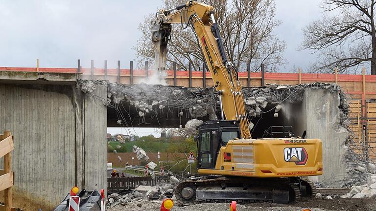 Der Bagger mit dem Abbruchhammer leistet ganze Arbeit und bricht Stück für Stück aus der Autobahnbrücke heraus.