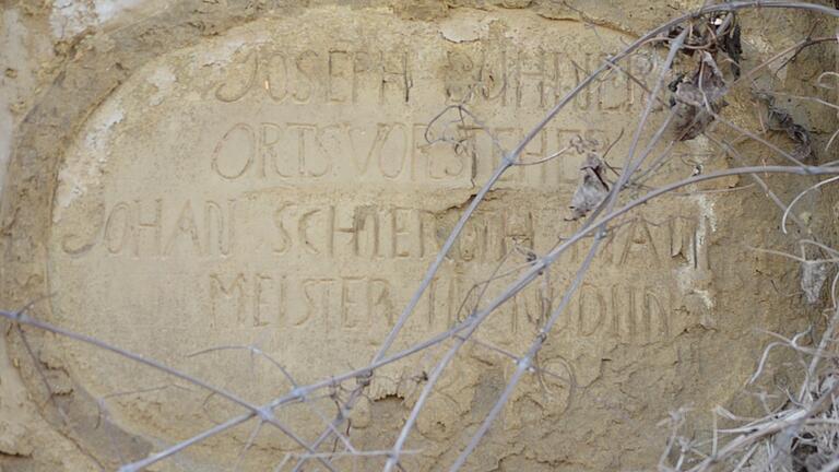 Die kleine Tafel am Eingang zum früheren Gasthaus 'Schwarze Pfütze' weist auf die Erbauer im Jahr 1819 hin: Der Rohbau wurde unter Ortsvorsteher Joseph Bühner vom Nüdlinger Maurermeister Johan Schlereth erstellt.