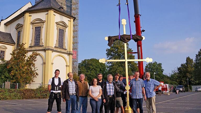 Der letzte Moment vor dem Hochziehen für die Handwerker und Verantwortlichen vor Ort. Im Beisein von Augustinerpater Christoph Weberbauer (rechts) wurde das Turmkreuz der Wallfahrtskirche auf der Kirchturmspitze montiert. Foto: Irene Konrad