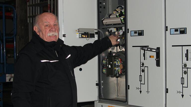 Elektromeister Hans-Georg Häfner an einem großen Schaltkasten für Mittelspannung, in dem viel Kupfer und Spannungsschienen aus Kupfer verbaut sind.