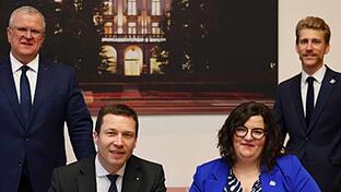Sparkassenpräsident Matthias Dießl und Carolin Hochmuth (sitzend, von links) unterzeichnen die Kooperationsvereinbarung zwischen den bayerischen Sparkassen und den Wirtschaftsjunioren Bayern. Dahinter Sparkassen-Vizepräsident Stefan Roßer (links) ...       -  Sparkassenpräsident Matthias Dießl und Carolin Hochmuth (sitzend, von links) unterzeichnen die Kooperationsvereinbarung zwischen den bayerischen Sparkassen und den Wirtschaftsjunioren Bayern. Dahinter Sparkassen-Vizepräsident Stefan Roßer (links) und Bernhard Fuchs (WJ Landesvorsitzender 2025). &#160;&#160;&#160;&#160;